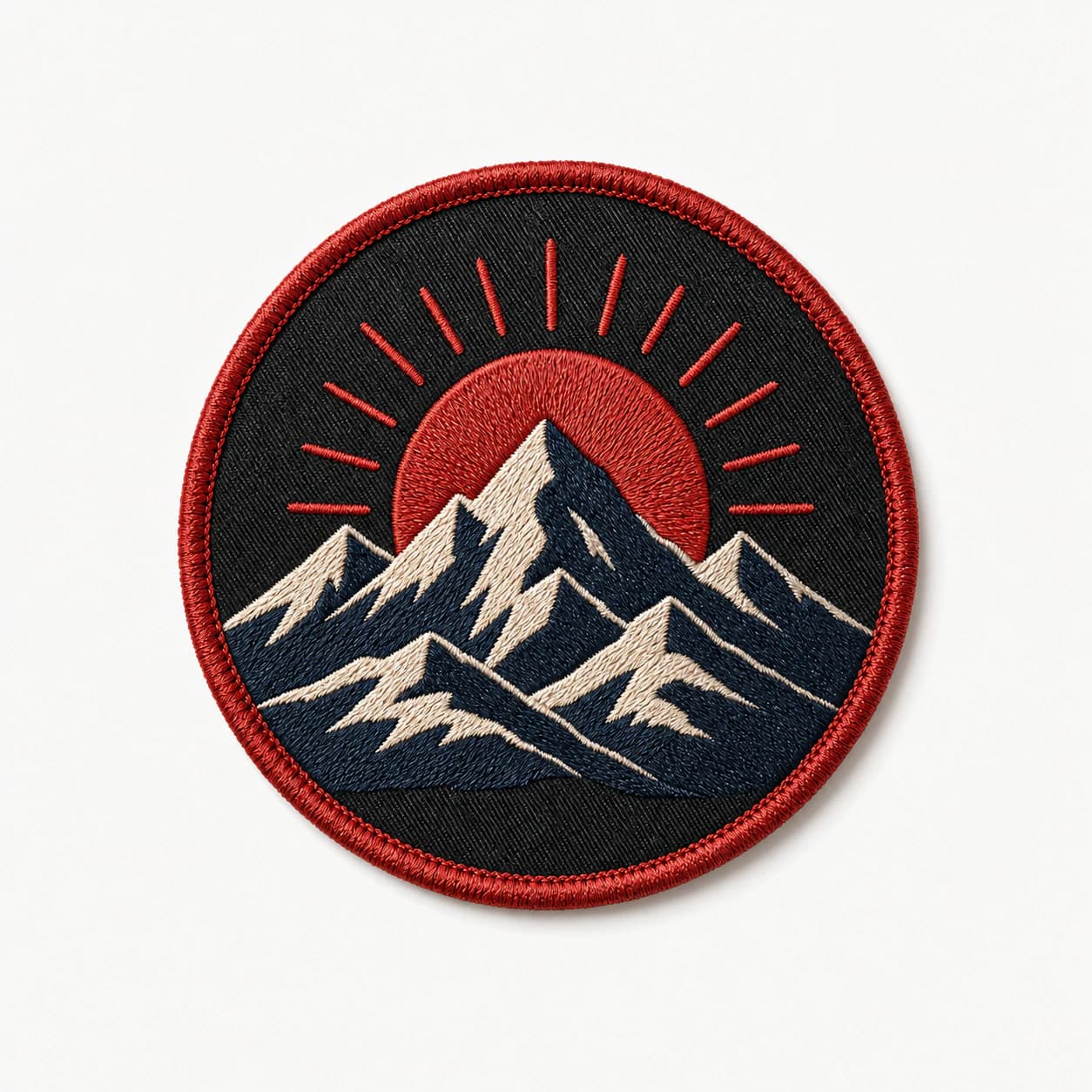 Round embroidered mountain patch in navy, cream, and red thread